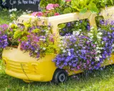 Un bus jaune transformé en jardinière déborde de magnifiques fleurs d'été aux teintes violettes, roses et blanches.